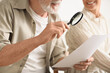 © Pixel-Shot - Mature couple looking at paper bill in kitchen, closeup