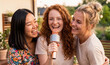 © Olena Smerichka - Three young friends singing karaoke together on a cozy summer home terrace.Warm sunset atmosphere with laughter, friendship and outdoor entertainment.