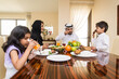 © oneinchpunch - Arab family wearing traditional emirati clothing bonding at home in Dubai