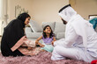 © oneinchpunch - Arab family wearing traditional emirati clothing bonding at home in Dubai