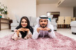 © oneinchpunch - Arab married couple wearing traditional emirati clothing at home - Middle eastern man and woman spending time together, domestic life in a traditional middle east family
