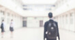 © al-sultan - A blurred image of a student walking in a school hallway. The background features other students and classrooms, highlighting an academic environment.