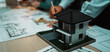 © InfiniteFlow - A detailed view of a modern house model placed on a table surrounded by architectural blueprints, showcasing the creative process of design and collaboration. SACTR