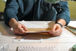 © New Africa - Man opening envelope with letter at white wooden table indoors, closeup