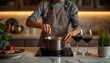 © Masaji - A person in an apron is stirring a pot on a modern induction cooktop with two glasses of red wine nearby.