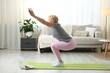 © New Africa - Senior woman practicing yoga via video chat with online coach at home. Fitness and sport