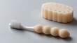 © BOJOShop - Close up of a white toothbrush with a textured handle next to a ribbed sponge