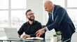 © twilight mist - Two smiling businessmen collaborate over documents and a portable computer in a bright office setting