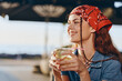 © SHOTPRIME STUDIO - Lifestyle woman in modern boho-western denim street style enjoying a drink, smiling brightly with film color tones under natural sunlight outdoors.