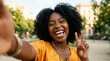 © AspctStyle - Happy young African American woman taking selfie showing peace sign in sunny park for lifestyle and social media concept