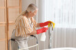 © Pixel-Shot - Mature woman with walker, detergent and rag cleaning faucet in bathroom