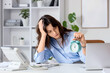 © Pixel-Shot - Stressed young businesswoman with alarm clock at her workspace in office. Deadline concept