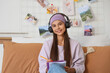 © Pixel-Shot - Teenage girl with headphones writing on notebook in bedroom
