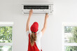 © Pixel-Shot - Female technician repairing air conditioner in room, back view