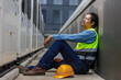 © eakgrungenerd - Man industrial worker sitting beside rooftop HVAC units, showing fatigue, burnout, stress and emotional despair after hard maintenance work in workplace.