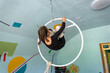 © Ольга Симонова - Girl hanging on aerial hoop during acrobatic training, focused on safety, wearing sport clothes and elastic wraps for legs.