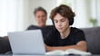 © DOUGLAS - Teenager laptop headphone study focus father background living room