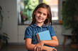© Jelena - Portrait of smiling schoolgirl holding books at home