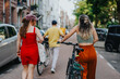 © qunica.com - Three friends walk and push their bicycles down a tree-lined city street in the Netherlands. Casual summer outing showing relaxed conversation and urban cycling culture.