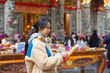 © leungchopan - Woman praying inside traditional temple interior