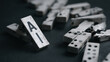 © Lumos Studio - A close-up of scattered dominoes with one standing upright, featuring the letters AI on it, against a dark background.