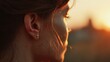 © Honey - A close-up portrait of a woman with a cross earring at sunset