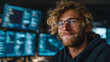 © CinimaticWorks - modern programmer at workstation with multiple computer monitors displaying code smiling confidently in a technology driven workspace focused on software development