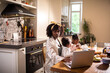 © Marko Geber - Mother working on laptop at kitchen table with children