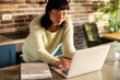 © Davor - Woman managing finances on laptop at home kitchen counter