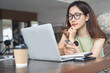 © tippapatt - Young asian business woman working at laptop thinking of problem solution, thoughtful female employee considering idea looking at laptop screen, making decision, close up