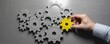 © Hasibnikon - Business professional placing yellow gear among silver gears on dark background for teamwork and success concept