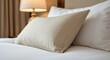 © The 2R Artificiality - Close up of a soft pillow on a luxury hotel bed with a lamp showcasing room decor and safety concepts