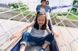 © Studio Marmellata - A young girl slides down a playground structure with her parents behind her, enjoying a fun day outdoors.