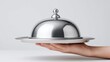 © RndVisuals - Hand holding a silver cloche on a plate, ready to serve a surprise dish