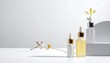 © Lilik - Three glass bottles with droppers, two with white and one with gold lids, with flowers, on a white surface with a minimalist background