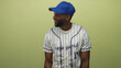 © Krakenimages.com - Baseball player man wearing pinstripe jersey and blue cap pointing finger to the left in studio against light green backdrop; team sport confidence.