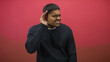 © Krakenimages.com - Man with beard holding hand to ear in listening gesture in studio with pink backdrop and navy sweater; curiosity.