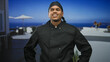 © Krakenimages.com - Hispanic man chef with hands on hips and a confident smile in a building terrace wearing black chef uniform and bandana; confidence professionalism.