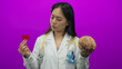 © Krakenimages.com - Young woman doctor with stethoscope holds brain and heart paper against pink background, symbolizing medical science and healthcare choices.