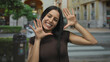 © Krakenimages.com - Woman smiling outdoors as she playfully gestures with hands on a vibrant city street, embodying joy and spontaneity in an energetic urban environment.