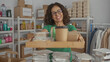 © Krakenimages.com - Woman in green uniform smiling indoors holding food tray in charity volunteer room with shelves and clothes around suggesting active participation and warmth