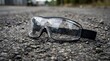 © Ahmad - Abandoned safety goggles lie on rough outdoor asphalt surface near industrial area
