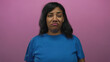 © Krakenimages.com - African american woman grimaces in studio with purple backdrop wearing blue shirt and loose hair under soft lighting; disgust.