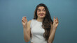 © Krakenimages.com - Hispanic woman holding fingers in air quotes with raised eyebrows and playful grin in a blue studio; sarcasm irony.