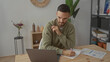 © Krakenimages.com - Young man working on laptop in a modern living room with charts on the table showcasing a productive home office environment.