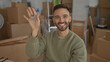 © Krakenimages.com - Young man smiling indoors holding house keys surrounded by cardboard boxes in a new home environment signifying a fresh start.