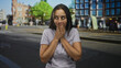 © Krakenimages.com - Woman covering mouth with hands on city street near tram tracks wearing t shirt, looking sideways with shy smile; surprise curiosity.