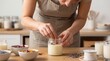 © Tatyana - Woman making scented candles with dried flowers in a cozy workshop