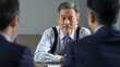 © bephoto - オフィスで向かい合い真剣に話し合う日本人ビジネスマンの打ち合わせ