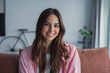 © Daniel - Happy attractive young adult woman housewife sitting on sofa looking at camera in modern cozy home, smiling single 20s lady beautiful face relaxing on couch alone enjoy wellbeing posing for portrait